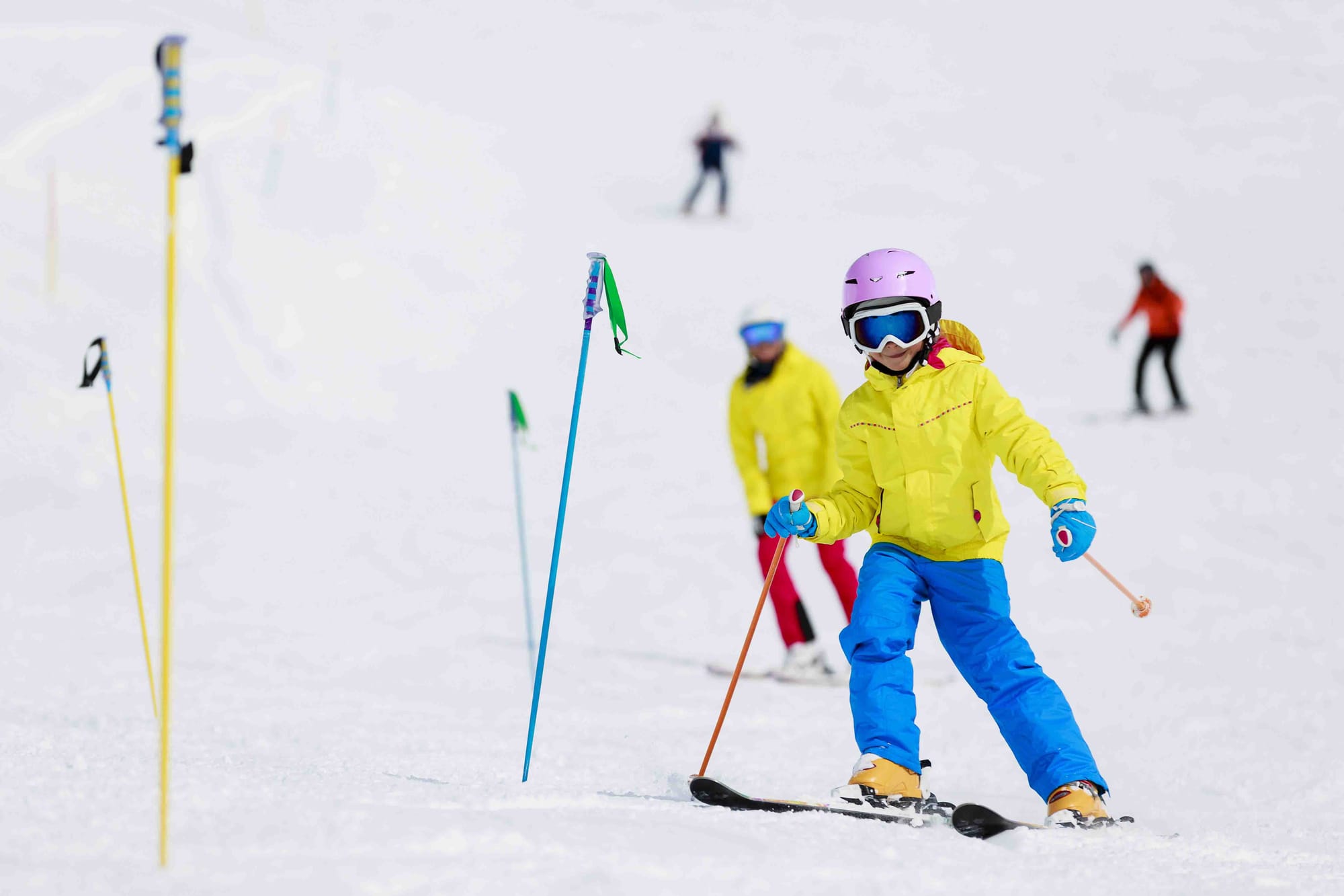 Child in a ski lesson practising going round slalom poles