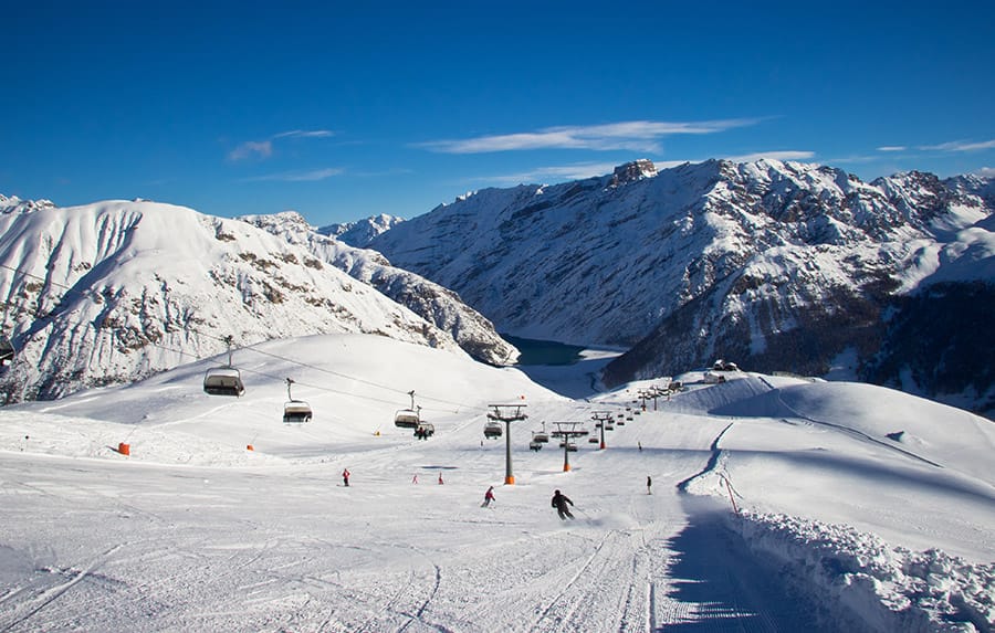 Ski slope in Livigno with chairlift coming up it and blue skies