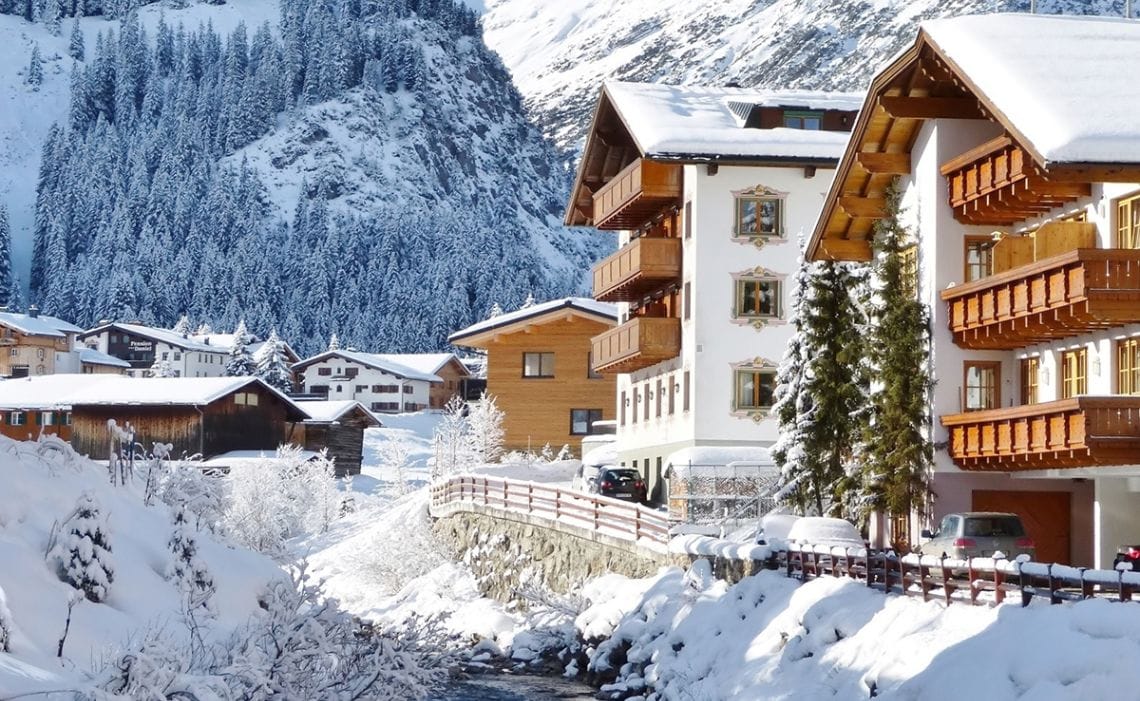 Buildings in Lech next to a river and with mountain backdrop