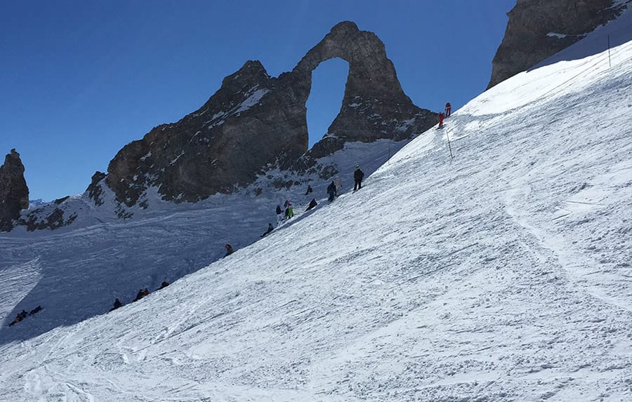 Eye of the needle (Aiguille Percees) - large rock formation with hole in the middle and skiers nearby