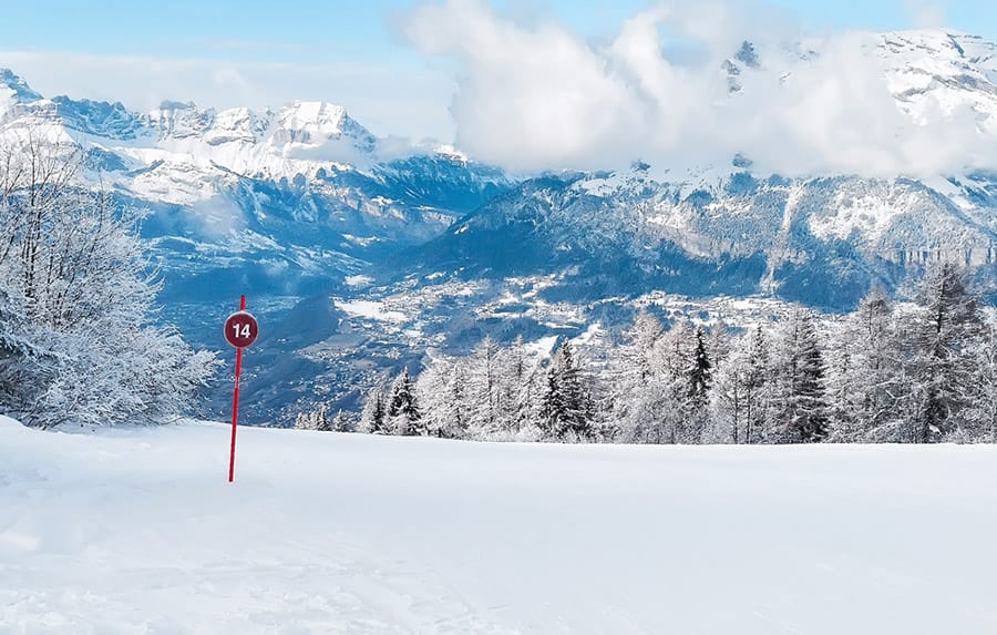 Sign showing the start of a red run in Chamonix, with dramatic mountain backdrop behind