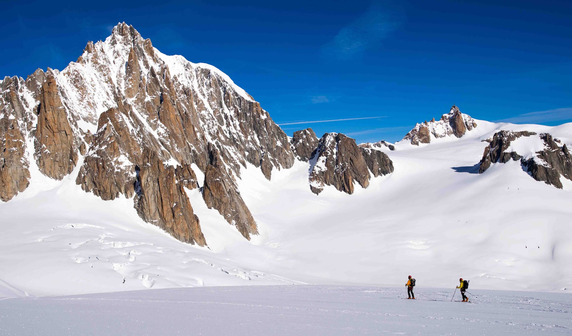 2 skiers travel past rocky outcrop