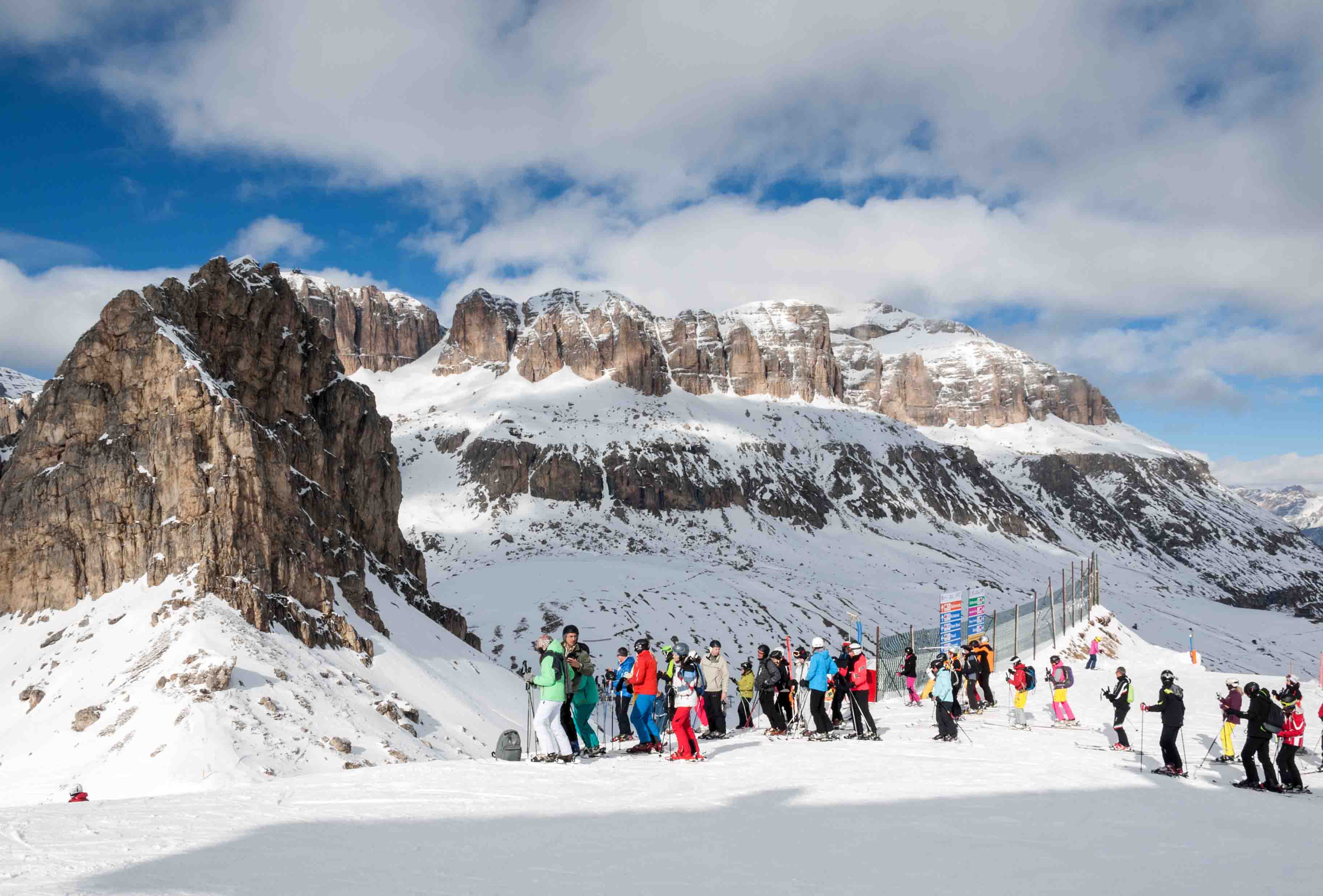 Skiers wait at top of ski slope with rocky outcrop nearby