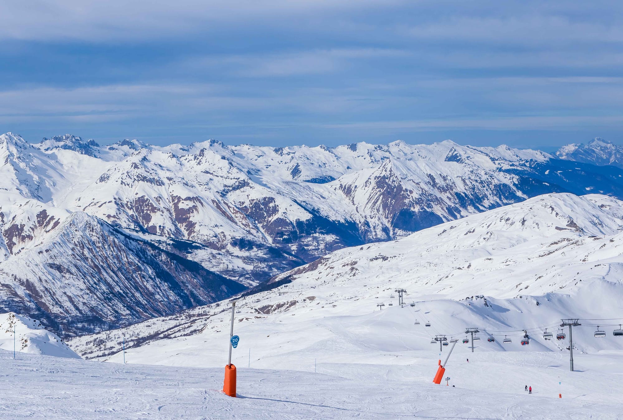 Rolling snowy hills with a 4-person chair lift ascending on a slightly cloudy day.