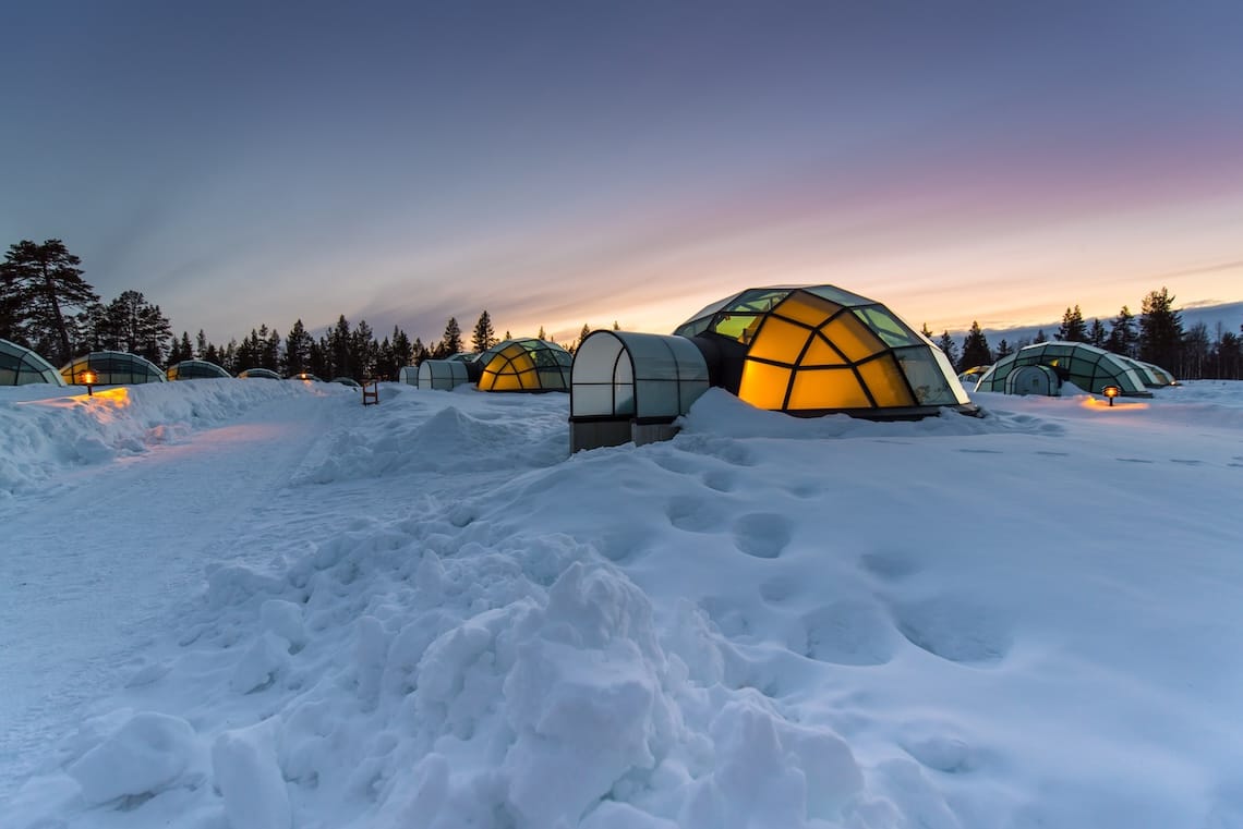 Glass igloos in a snowy landscape surrounded by forest