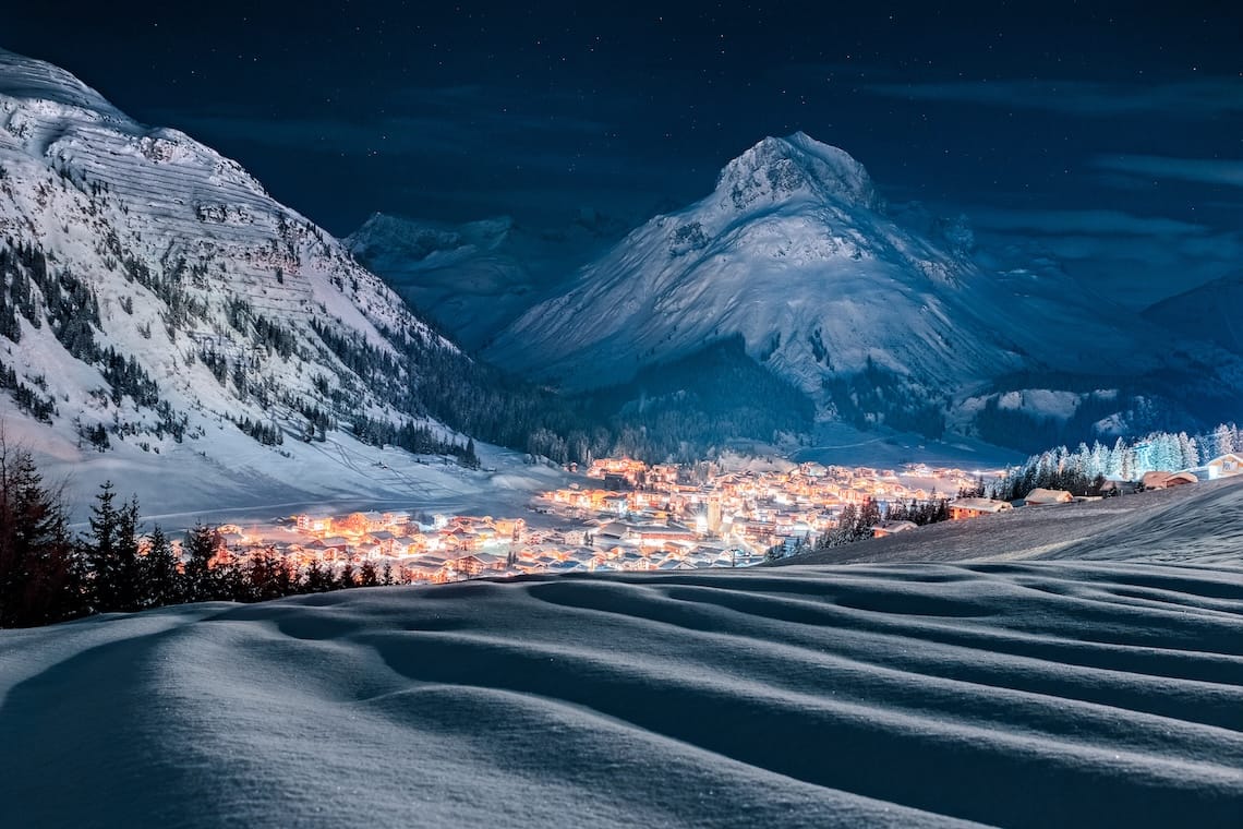 Snow-covered Lech ski resort under starry night sky