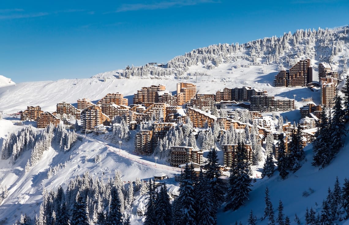 Wood-clad high rises of Avoriaz ski resort on the mountainside under clear blue skies