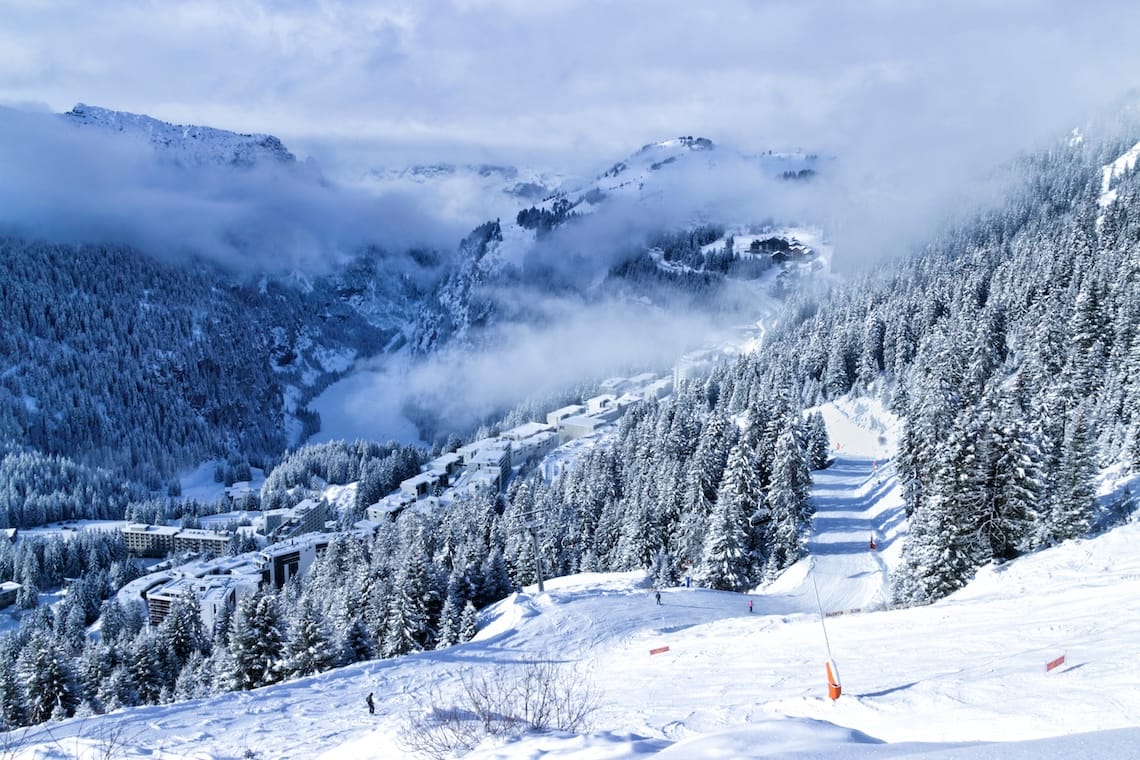 Tree-lined piste under cloudy skies above Flaine ski resort