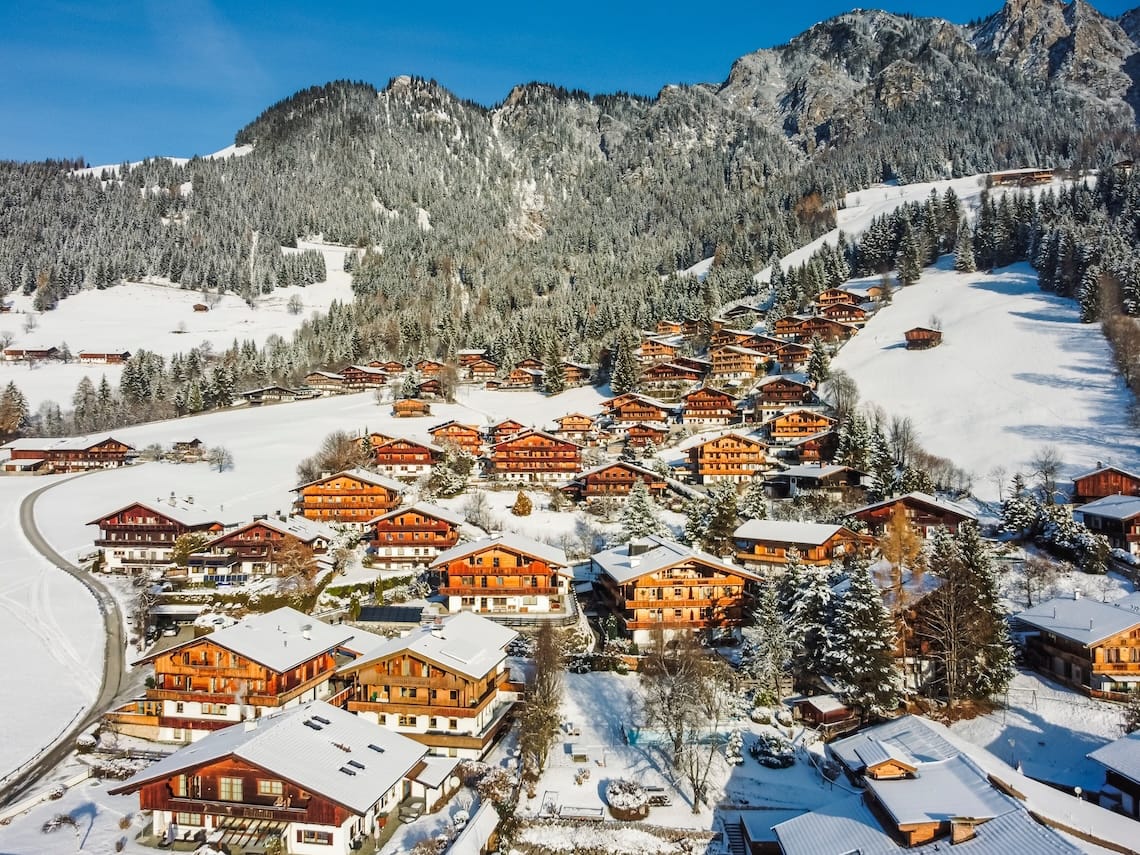 Aerial view of Alpbach under blue skies with mountain backdrop 