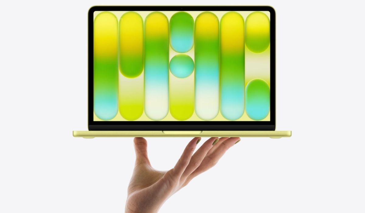 Product shot of the MacBook Neo with a hand holding it up