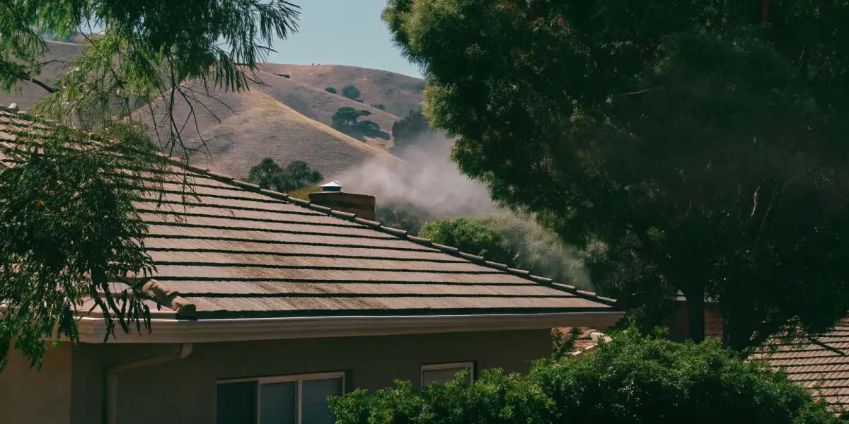 A roof vent emitting smoke, a critical entry point for wildfire embers without a proper guard.