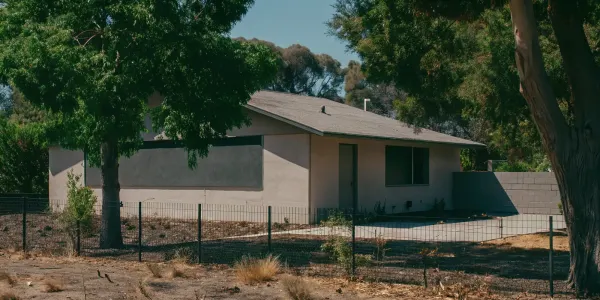 House in dry brush, illustrating wildfire insurance risk.