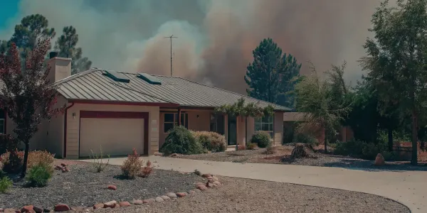 A home with fire resistant improvements and landscaping, protected from a wildfire in the background.