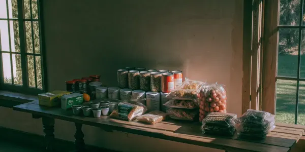 A collection of non-perishable food for an emergency kit, including canned goods, grains, and water.