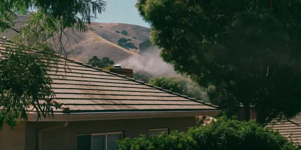A roof vent emitting smoke, a critical entry point for wildfire embers without a proper guard.