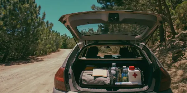 A complete car emergency kit for the road, with first aid supplies and water organized in a trunk.