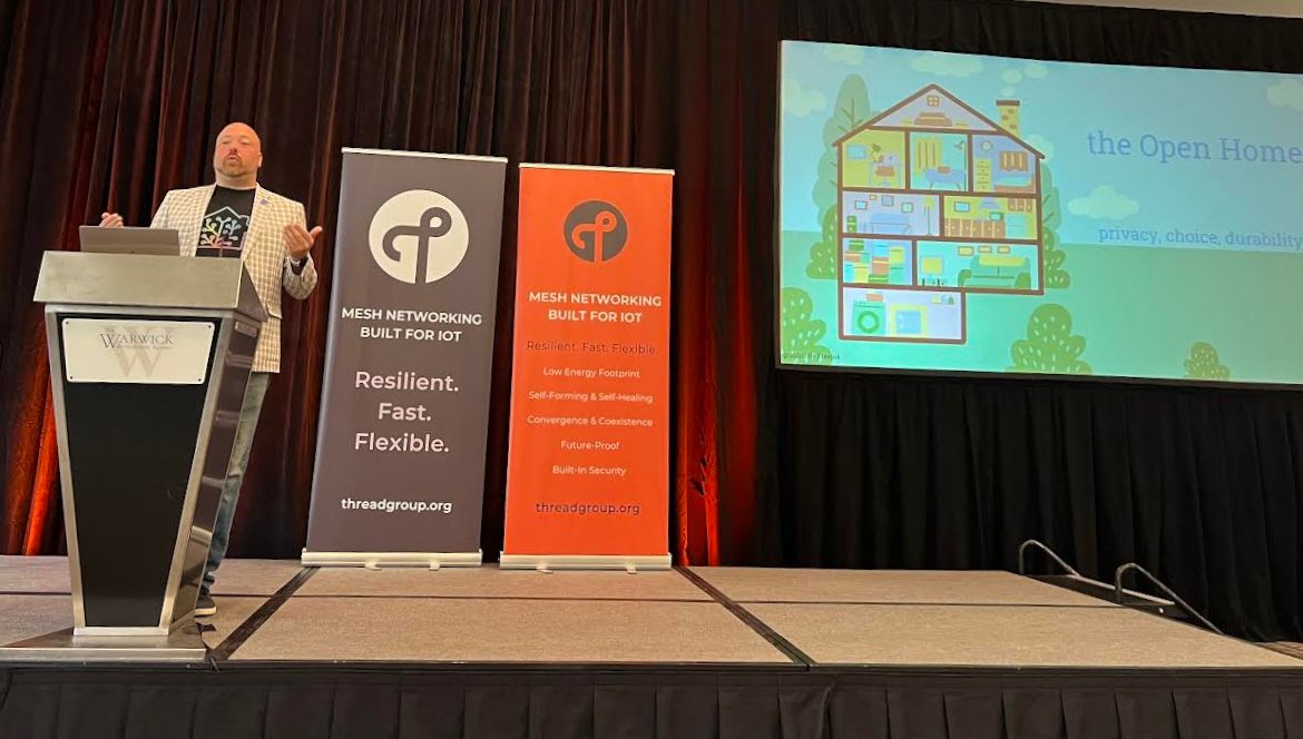 Photo of Paulus Schoutsen on a stage with an Open Home slide projected.