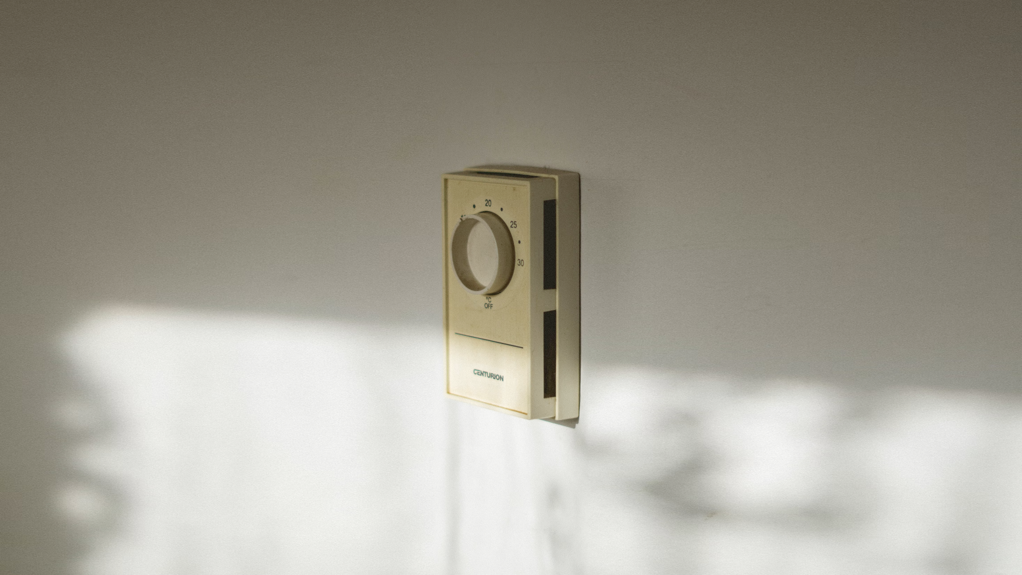 A photo of an old thermostat that is so old that the plastic is discolored.