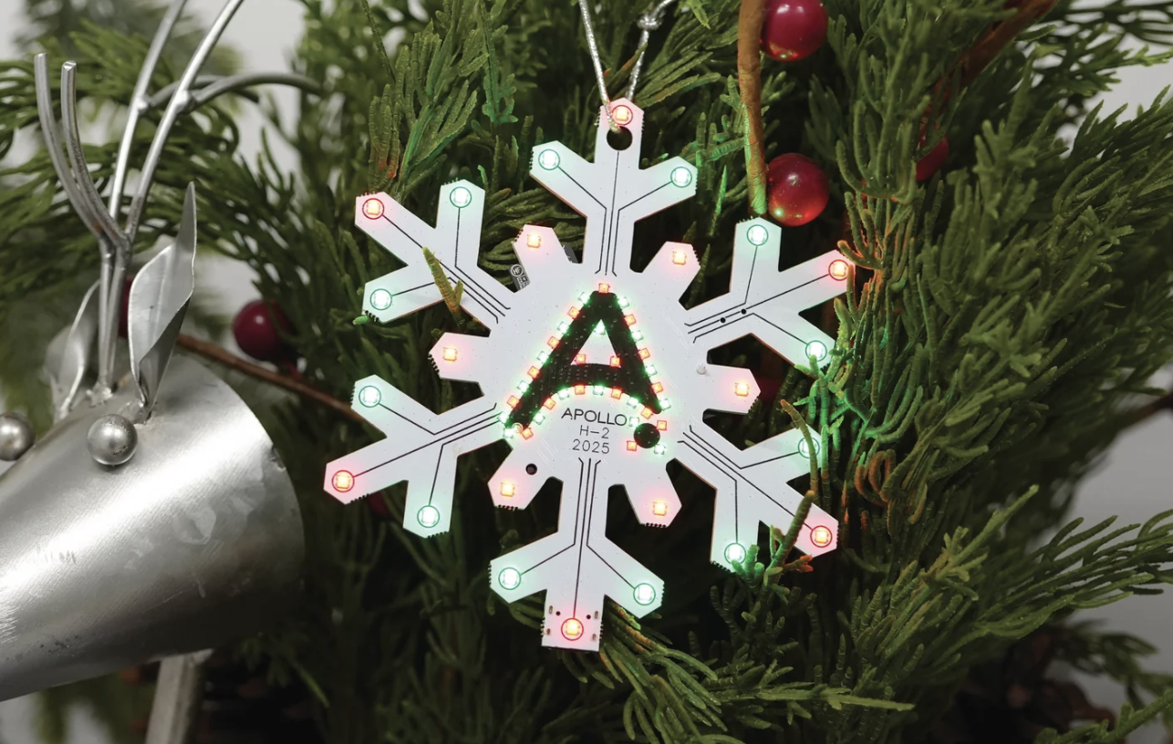An Apollo Automation light-up H-2 Holiday Ornament hanging from a Christmas tree.