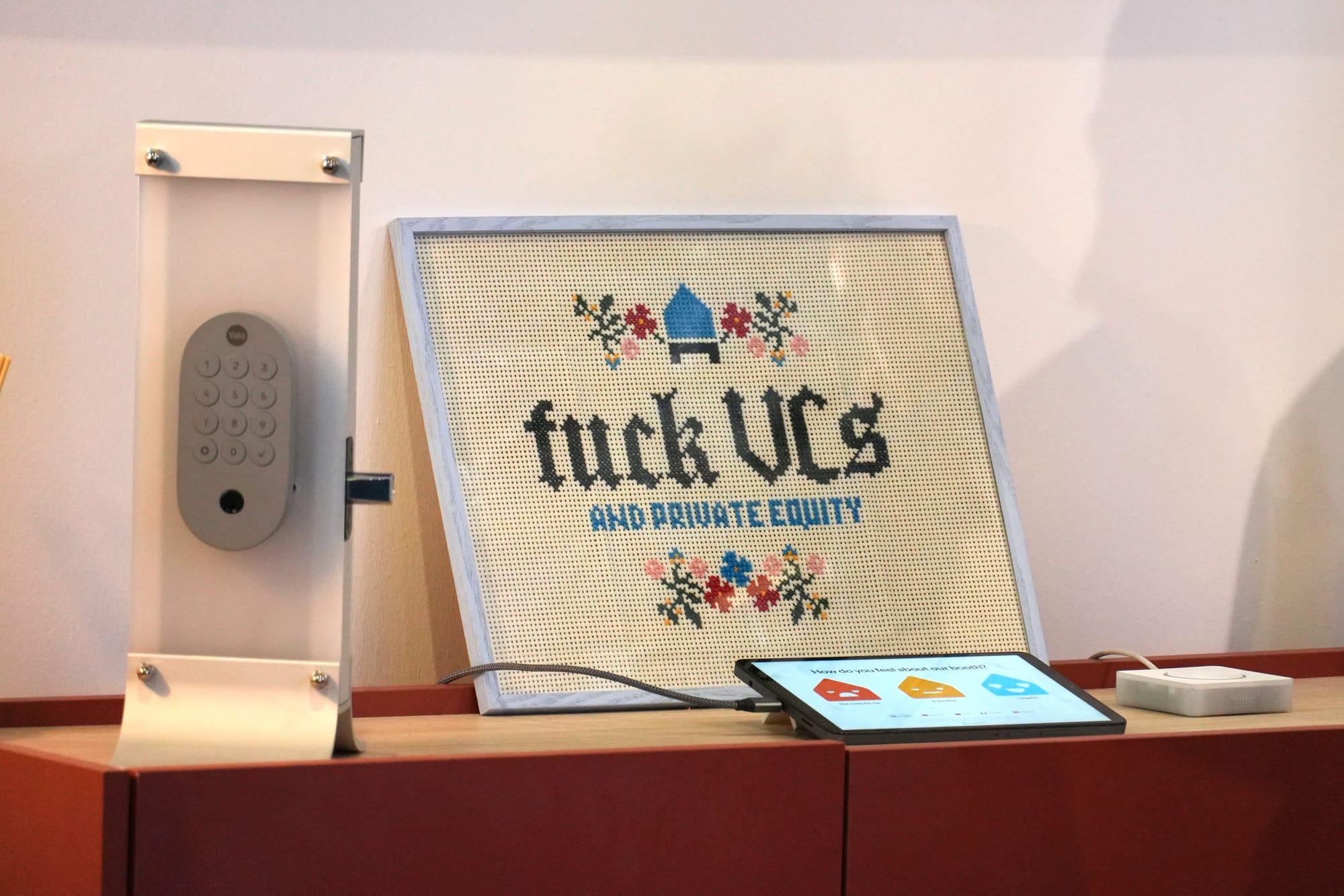 A photo of a framed cross-stitch with the words 'fuck VCs and private equity' stitched on it.