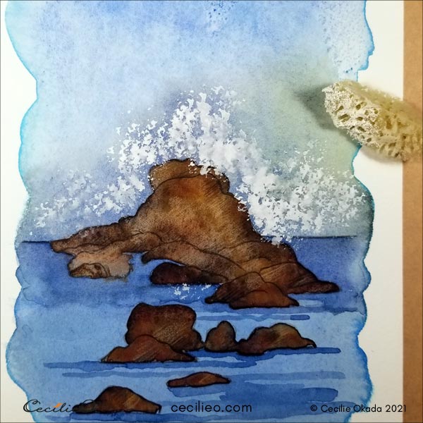 Using a natural sponge to create sea spray with white gouache. 