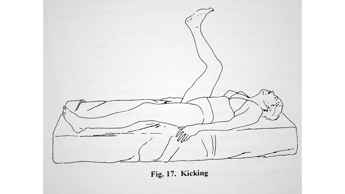 A line drawing of a woman lying face-up on a mattress. She is in her underwear, gripping the sides of the mattress and kicking with her legs. The caption reads "Fig. 17. Kicking"