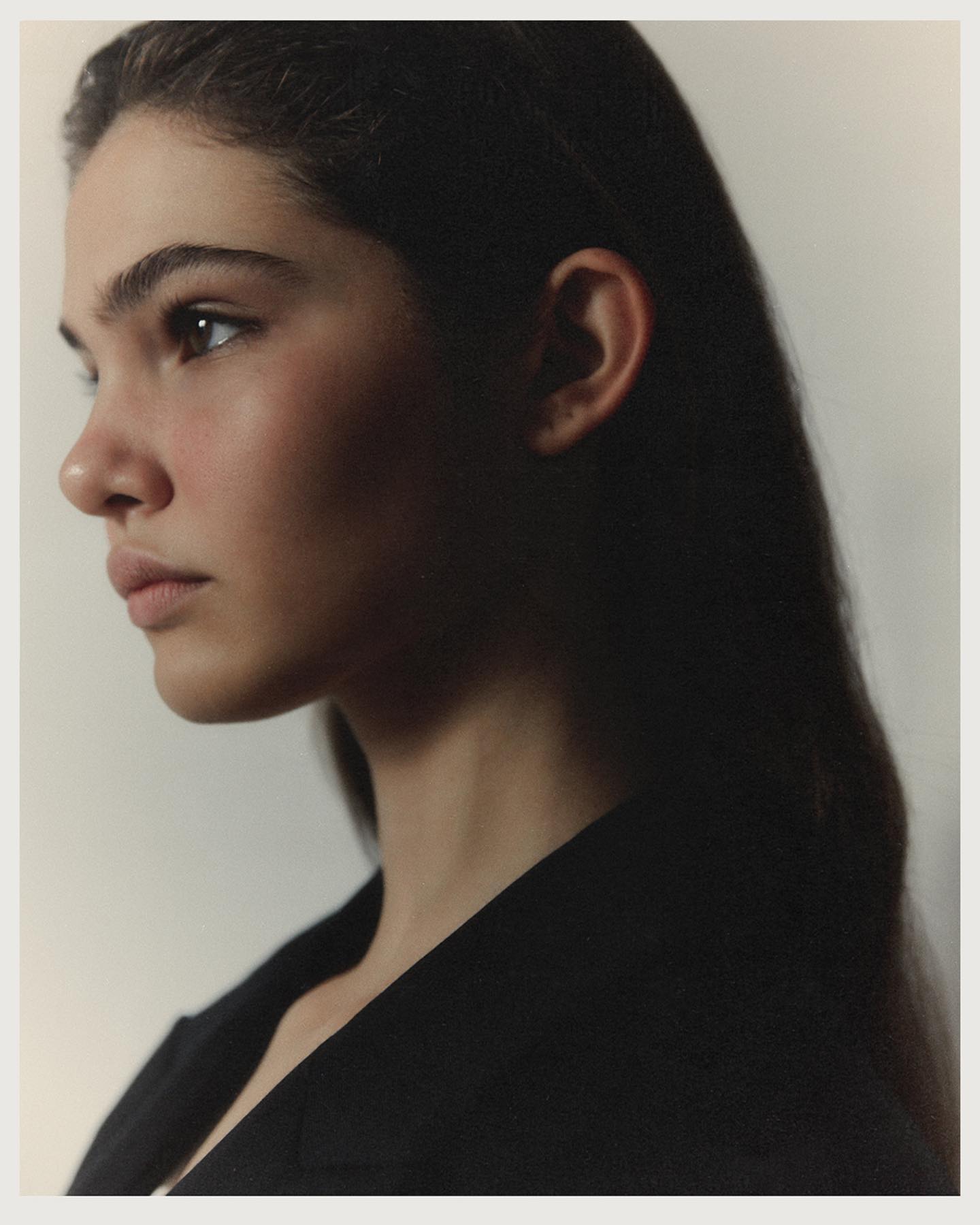 A close profile portrait of Anna in a black top, soft light catching her cheekbone and jawline, photographed by Ksenya Poggenpohl.