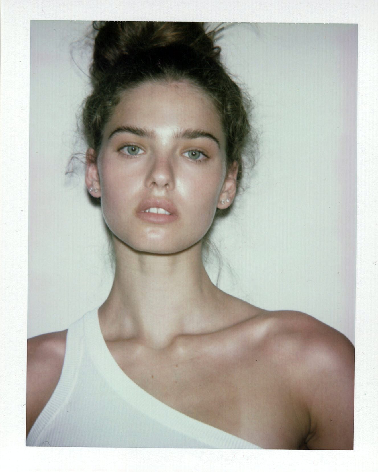 Close-up of Maya Norman's face in a white one-shoulder top, hair pinned up, shot on instant film by Bellezzamodaph.