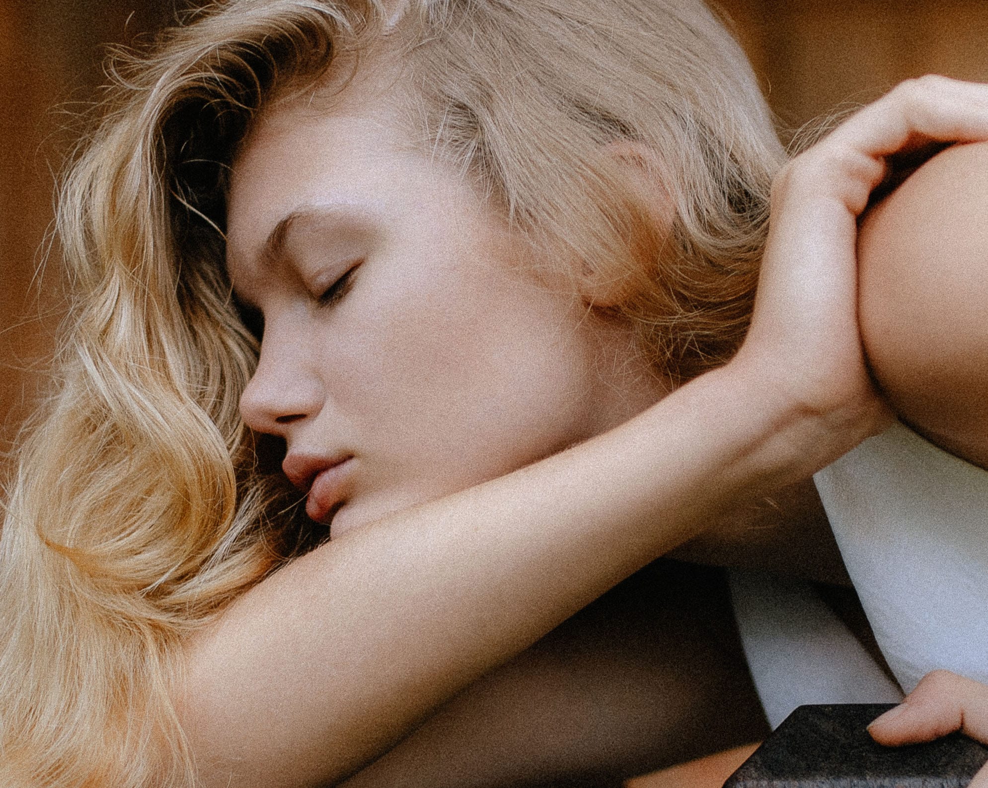 Close-up of Eva resting her face on her arm with eyes closed, warm golden tones, photographed by Tanya Xmyra.
