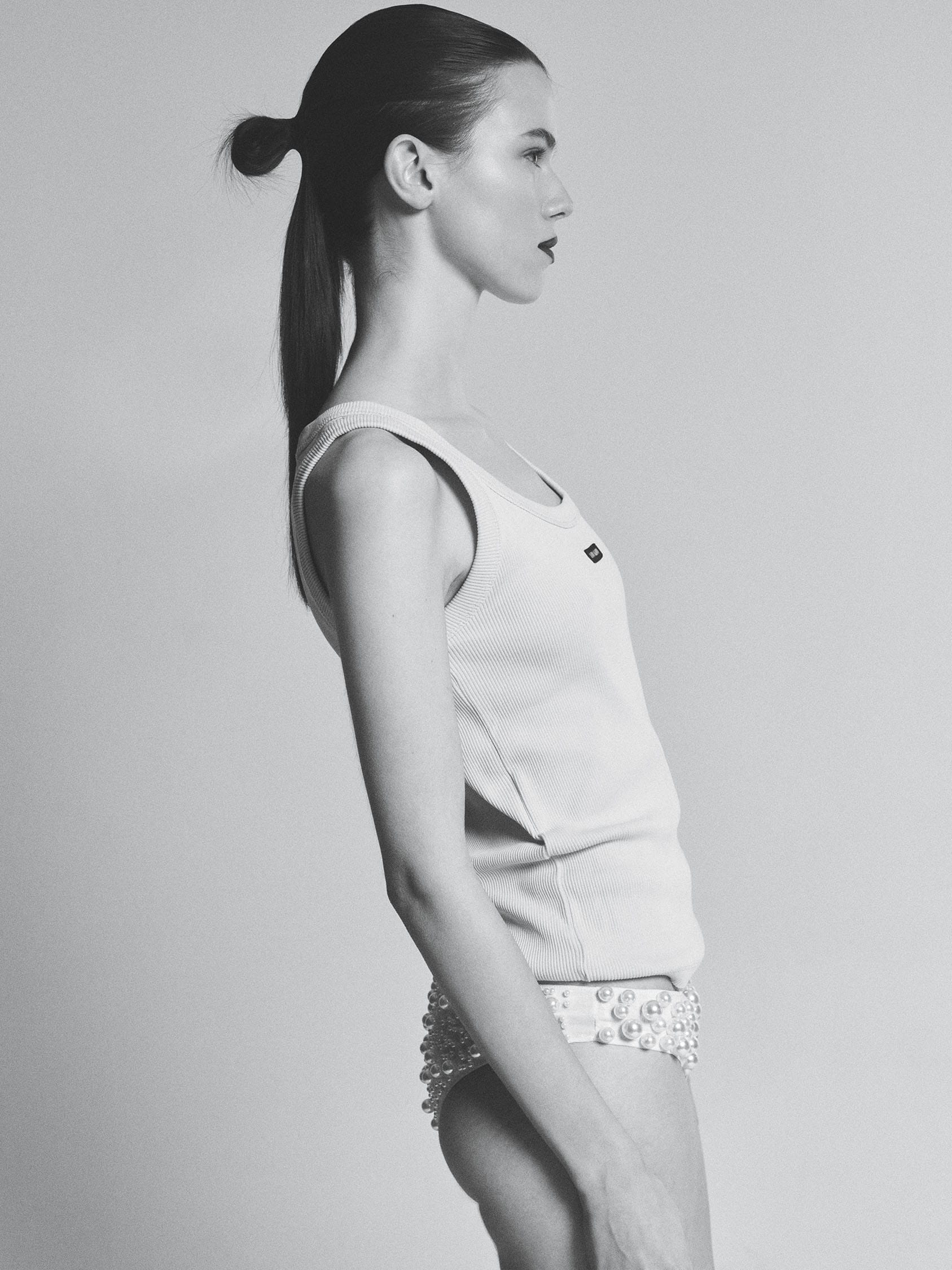 Greta Dethlefs in profile in a Miu Miu ribbed tank and pearl-encrusted briefs, hair tied back, photographed by Pascal Bräuer.