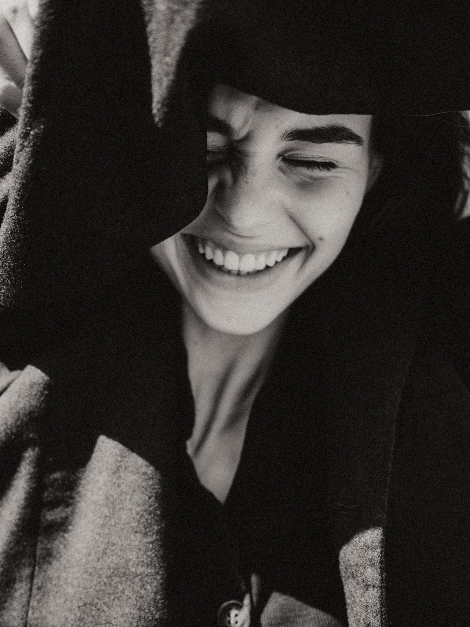 Tight shot of Giulia Bonatesta laughing under a draped blazer, photographed by Charles Cave.