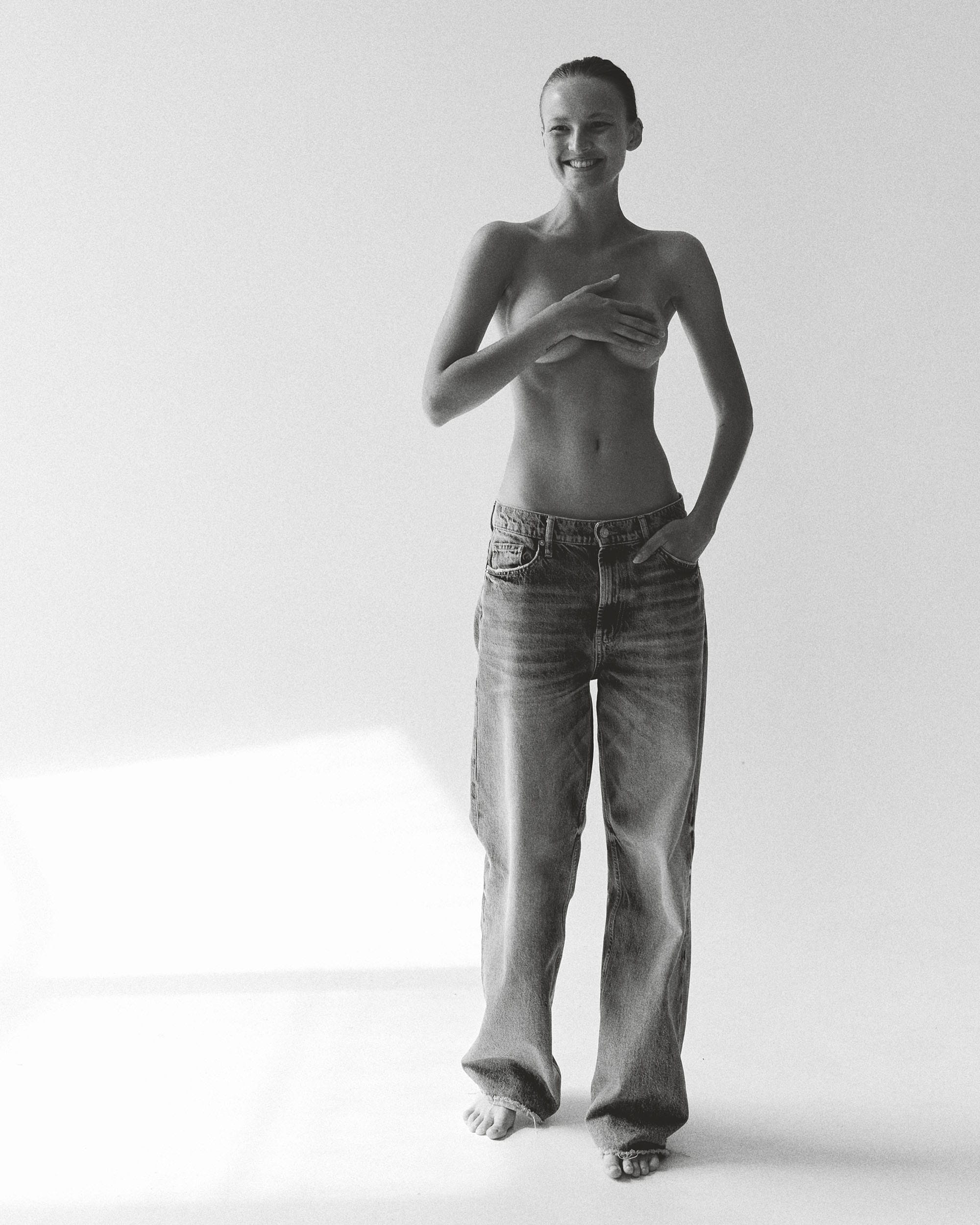 Tanya Korné stands barefoot smiling with one hand pressed across her chest, photographed by Darya Abramova.