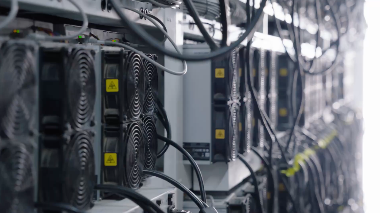 Row of professional air-cooled ASIC miners connected with industrial cabling inside a climate-controlled Simple Mining data center in Cedar Falls, Iowa.