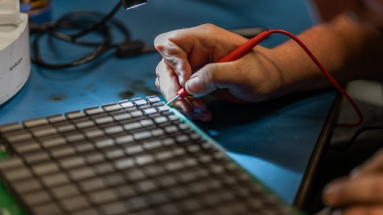 Simple Mining technician probing ASIC chips on a pulled hash board during diagnostic testing at the Cedar Falls repair bench.
