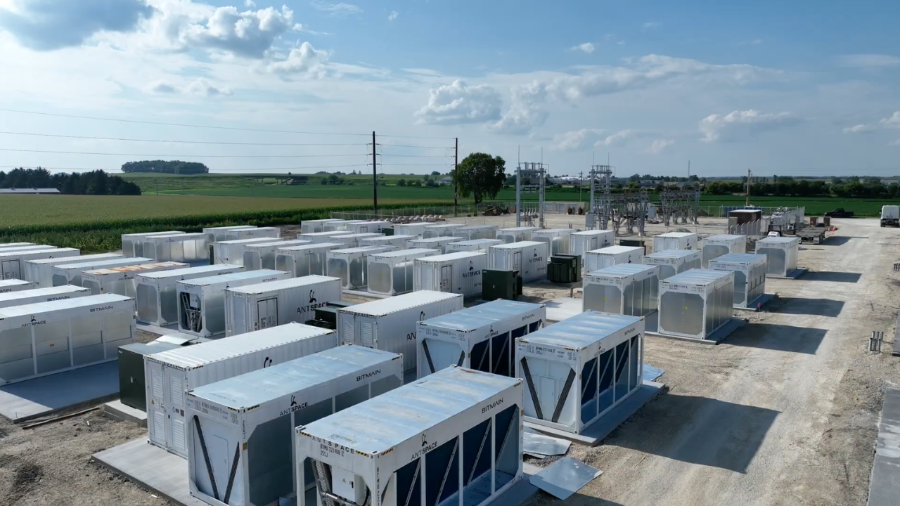 Aerial view of Simple Mining's Cedar Falls, Iowa Bitcoin mining facility showing rows of Bitmain Antspace containers and an on-site substation with farmland in the background.