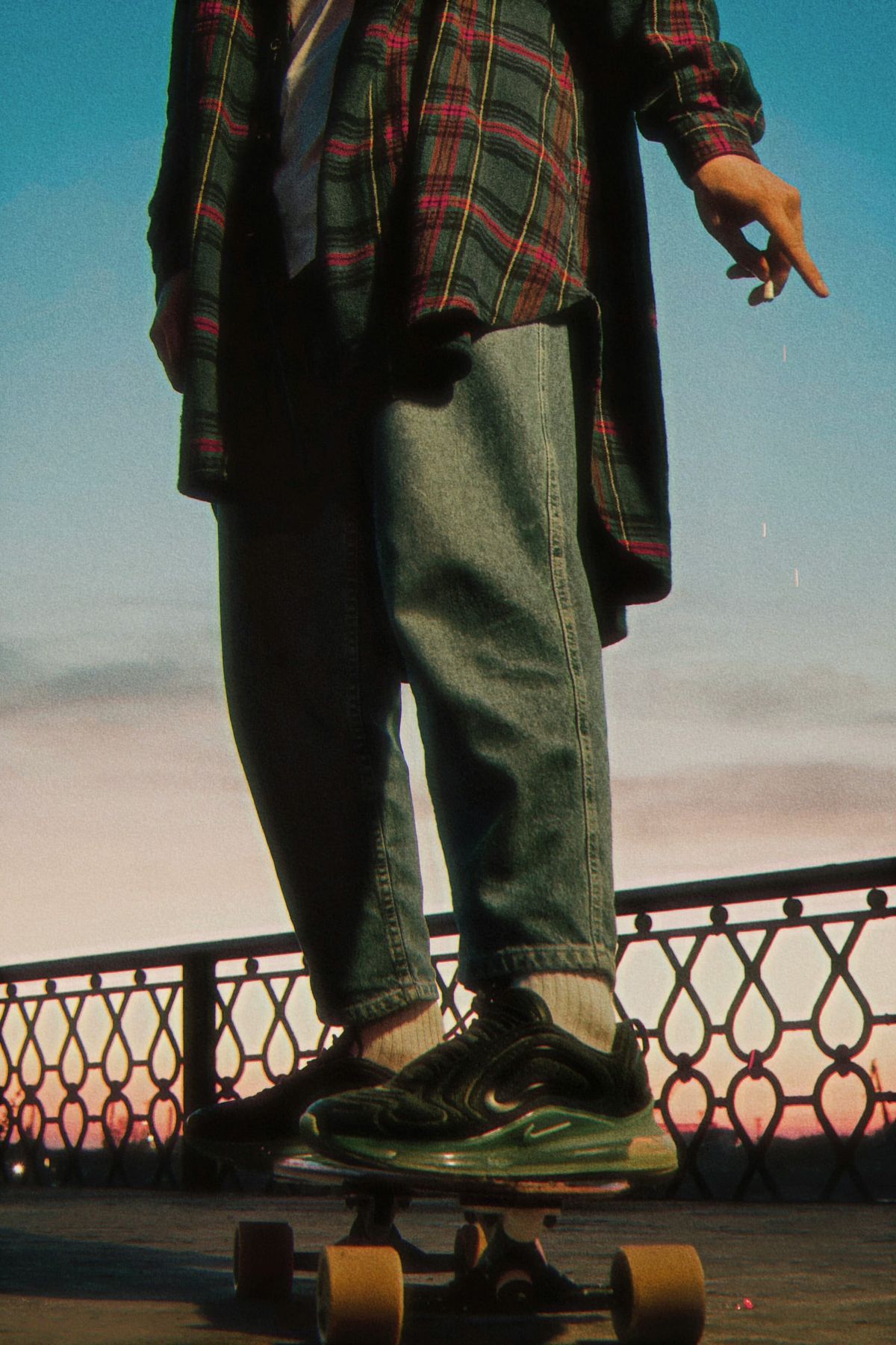 Skateboarde in a flannel shirt with a cigarette.