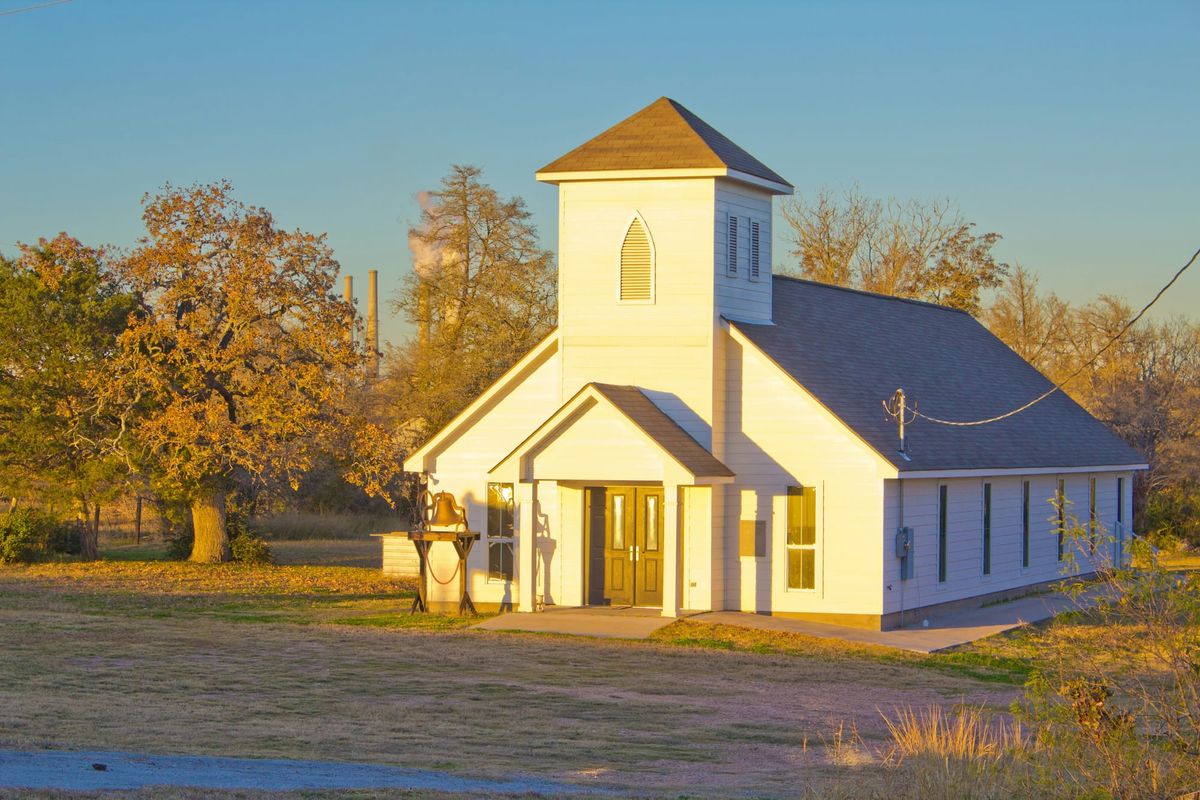 A church in a grassy clearing surrounded by trees