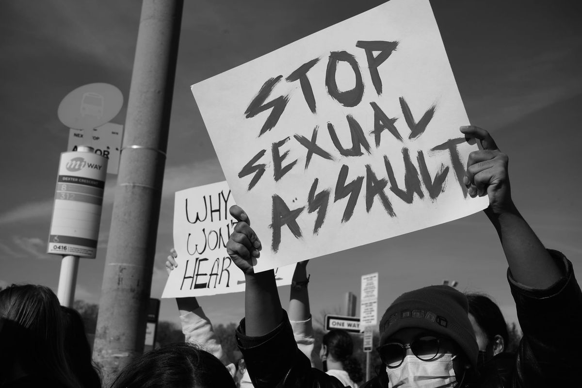 protestor with a sign that says "stop sexual assault" 