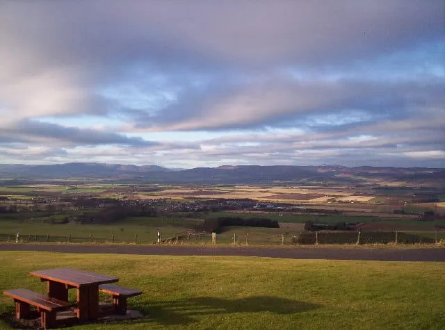 A view of the pastoral Mearns in Aberdeenshire. A picnic table in the foreground and in the background is the Eastern Cairngorms. It's an overcast day, which creates pretty lighting in the p