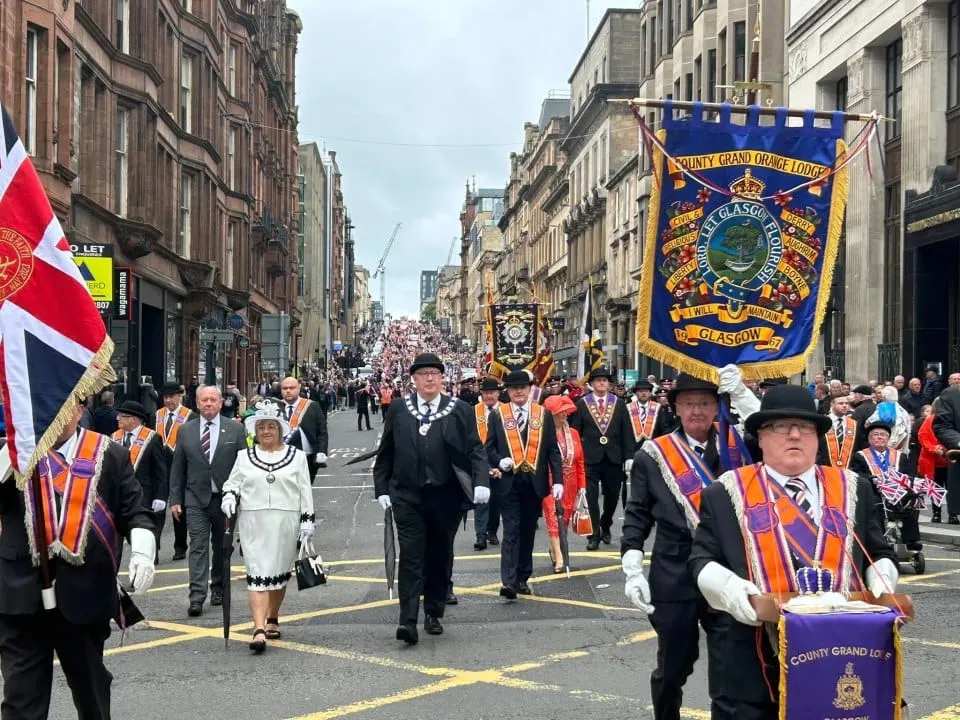 A long procession of hundreds of mainly men make their way down a central Glasgow street.