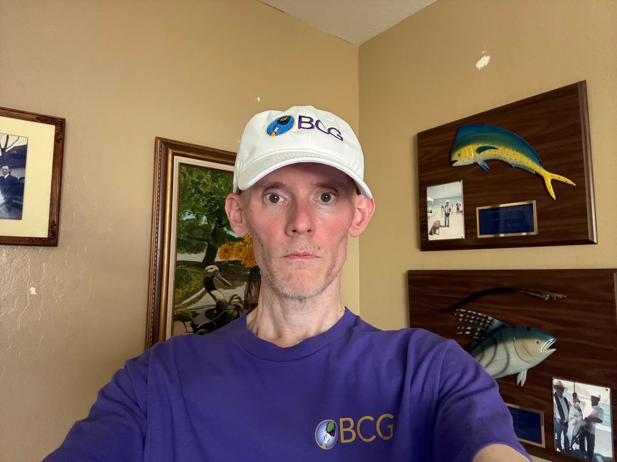 Eric Butow wearing his white Butow Communications Group (BCG) ballcap and purple BCG shirt.