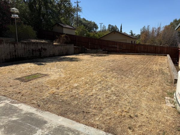 A flat space of brown grass in Eric's backyard with imprints of large play structures that were removed.