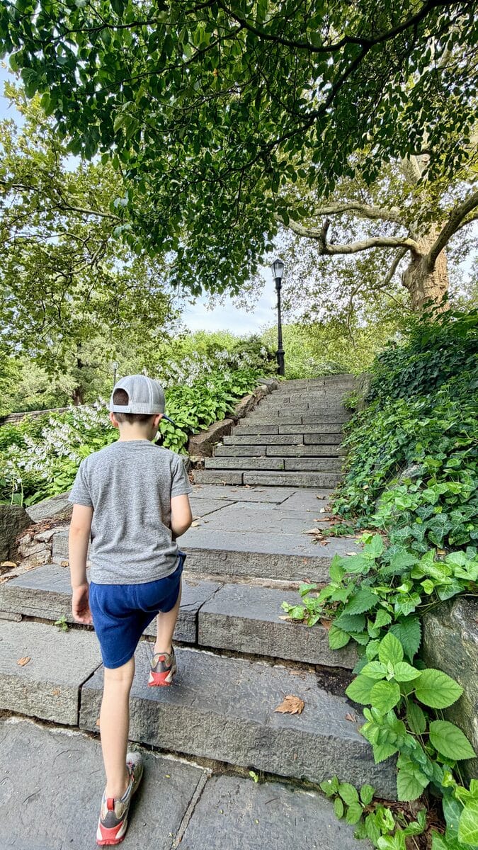 A child navigating the stone steps through Fort Tryon Park