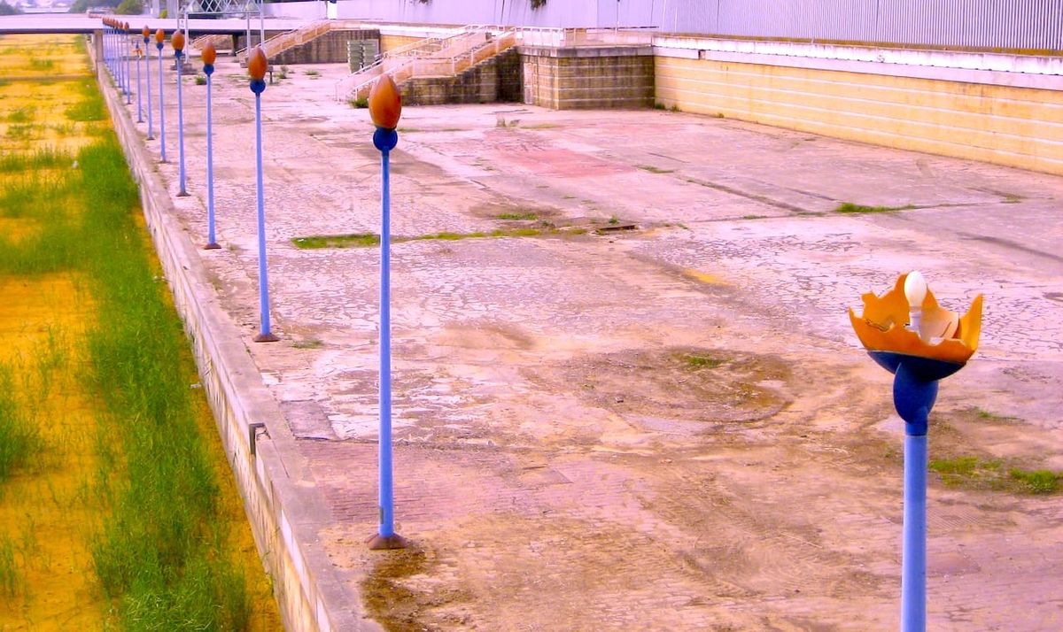 a row of light fixtures line the edge of a concrete platform outside sevilla, españa. 