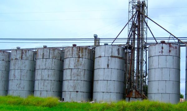 a row of metal silos and some kind of pipe contraption nearby.