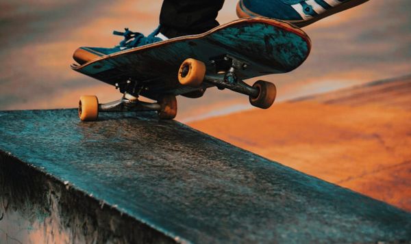 a skateboard with shoes on them does a little hop off a ramp.