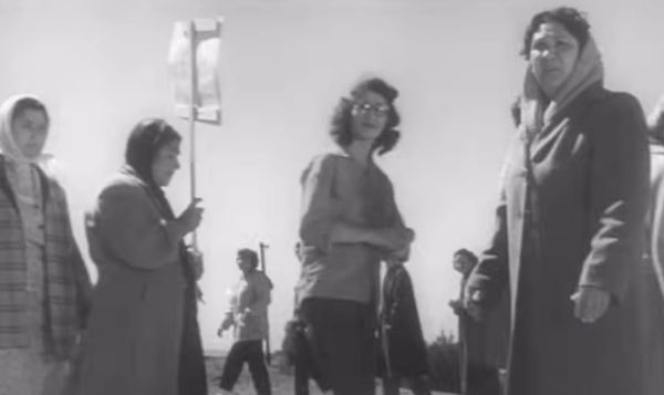 still from the film 'Salt of the Earth'. a circle of women hold signs for the picket line at the entrance to a zinc mine.