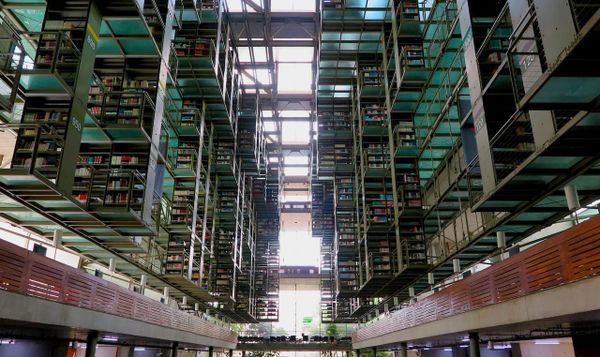 view from the ground floor of biblioteca vasconcelos, a public library in mexico city. shelves of books jut out towards the center of the room.