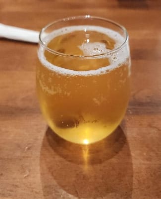Glass of apple juice and pear vodka; it looks golden and fizzy