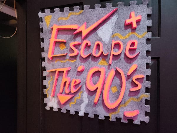 Felt sign on a door reading ESCAPE THE 90'S